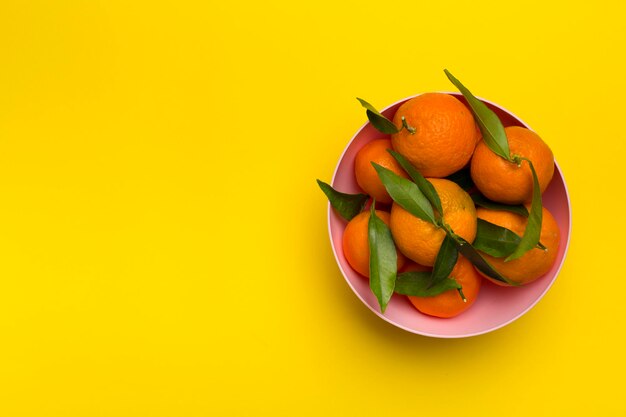 Fresh mandarines in bowl on color background Top view