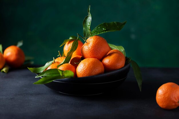 Fresh mandarins with green leaves on the dark background, selective focus image
