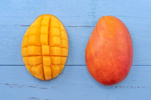 Fresh mango - beautiful chopped fruit with green leaves on bright blue timber background