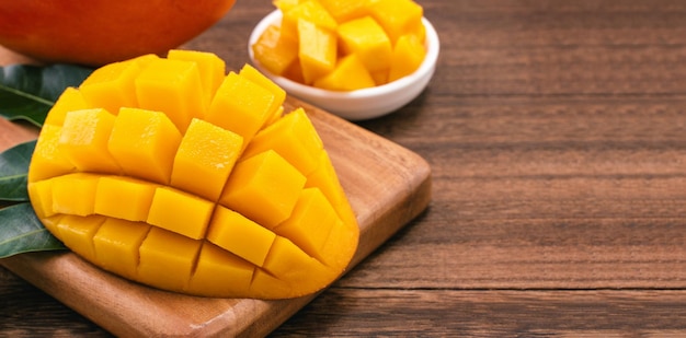 Fresh mango juicy chopped mango cubes on wooden cutting board and rustic timber background tropical summer concept close up macro copy space