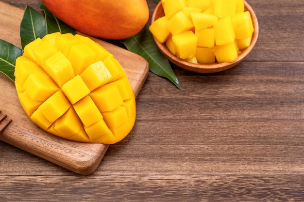 Fresh mango juicy chopped mango cubes on wooden cutting board and rustic timber background tropical summer concept close up macro copy space