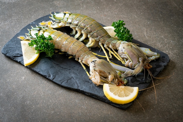 fresh mantis shrimp with lemon on black board