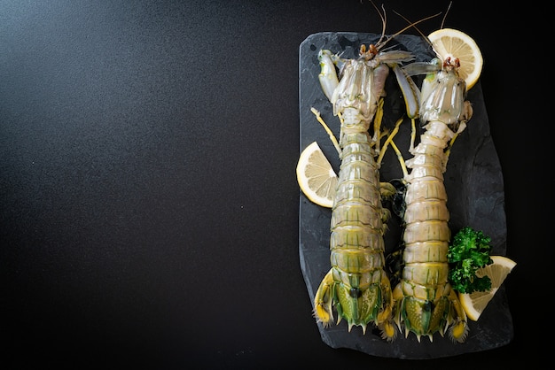 fresh mantis shrimp with lemon on black board