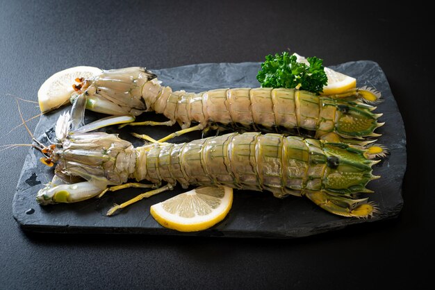 fresh mantis shrimp with lemon on black board