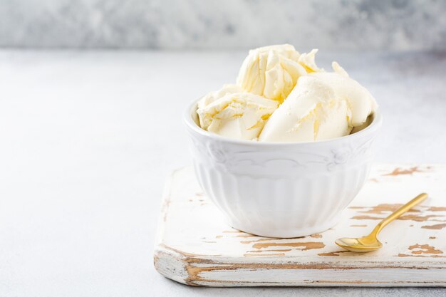 Fresh mascarpone cheese in a white bowl for making Italian tiramisu dessert on light background. Selective focus.