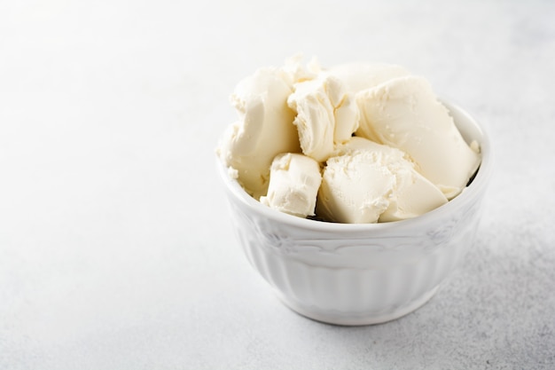 Fresh mascarpone cheese in a white bowl for making Italian tiramisu dessert on light