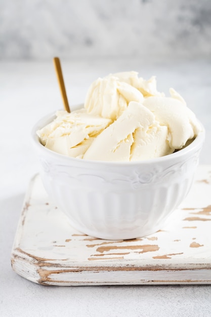 Mascarpone fresco in una ciotola bianca per preparare il dessert tiramisù italiano sulla luce