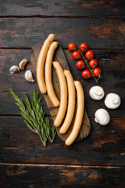 Set di salsicce per hot dog di carne fresca, su vecchio sfondo di tavolo in legno scuro, vista dall'alto piatta, con spazio di copia per il testo