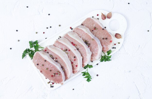 Fresh meat or raw pork steak with herbs and spices top view