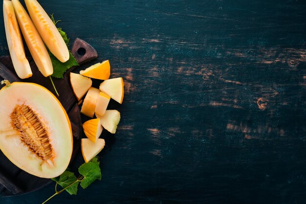 Fresh melon Sliced to pieces of melon On a black wooden background Free space for text Top view