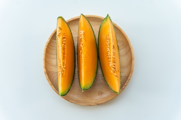 Fresh melons sliced on wooden plate on white table background