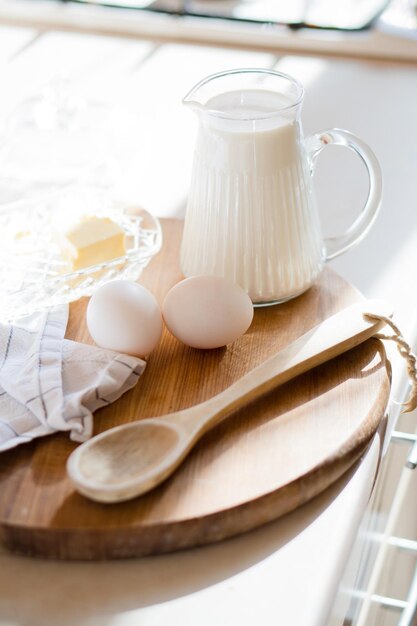 Fresh milk and eggs on wooden board in real home kitchen interior with natural light