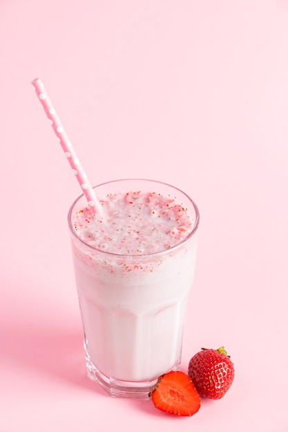 Fresh milkshake with strawberries on a pink background Summer drink with berries in a glass