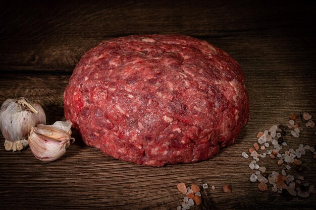 Fresh minced beef on cutting board on dark background with ingredients for cooking top view