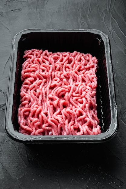 Fresh minced meat in plastic box packaging tray, on black