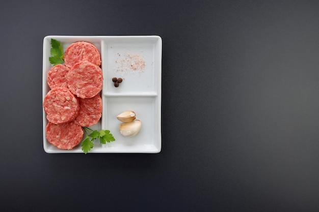 Fresh Mini beef burgers in a square plate on a gray background Raw semifinished meat products