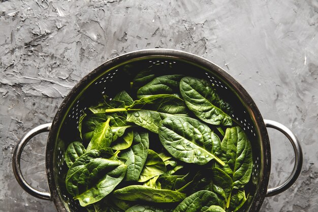 Fresh mini spinach in a colander on the old concrete table