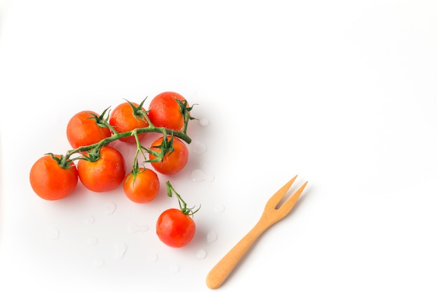 Fresh mini tomatoes whit wooden fork on white background