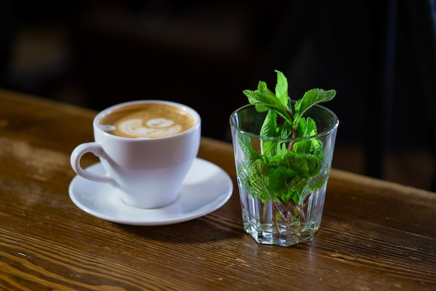 Fresh mint in a glass and a cup of latte art coffee on a wooden table