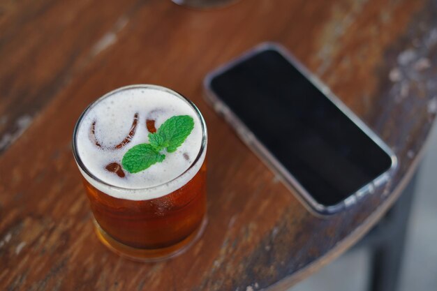 Foto tè freddo alla menta fresca sul tavolo con accanto un telefono