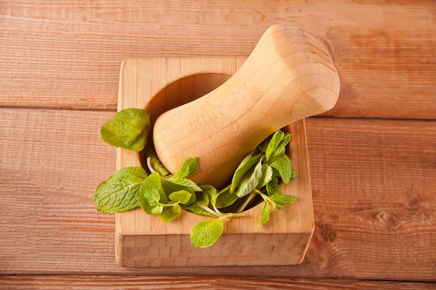 Fresh mint, wooden mortar, pestle on the wooden table.