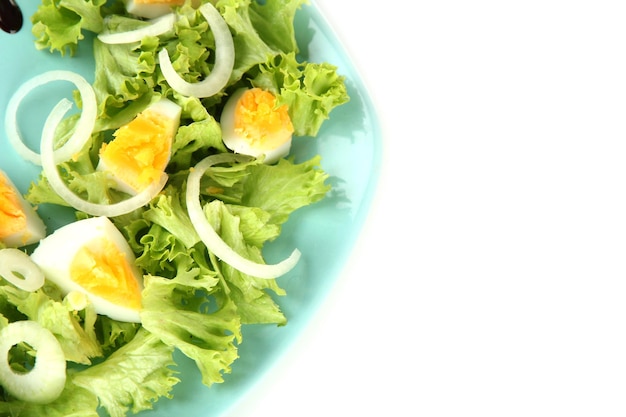 Fresh mixed salad with eggs salad leaves and other vegetables on color plate isolated on white