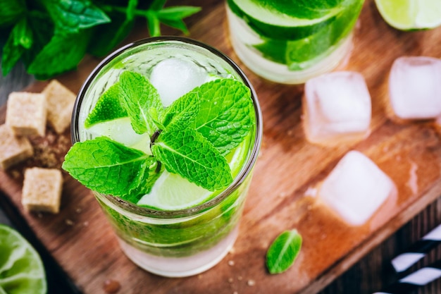 Fresh mojito cocktails with lime mint and ice in glass on wooden background