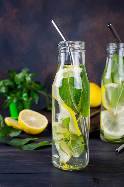 Fresh mojito drinks in bottles and ingredients - lemon and mint