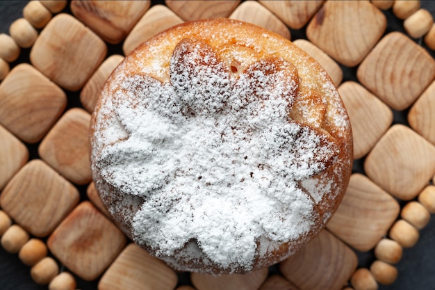 Photo fresh muffin muffin is sprinkled with powdered sugar top view of one muffin on a wooden surface