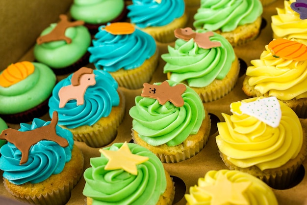 상자에 있는 어린이 생일 파티를 위한 신선한 여러 가지 빛깔의 컵케이크.