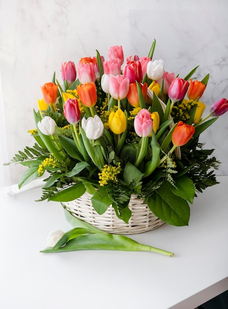 사진 발렌타인 데이 또는 여성의 날을 위한 바구니 선물에 든 신선한 여러 가지 빛깔의 튤립 꽃다발 낭만적인 생일 개념 밝은 배경