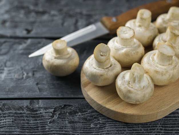 Fresh mushrooms are turned over on a cutting Board with a knife.