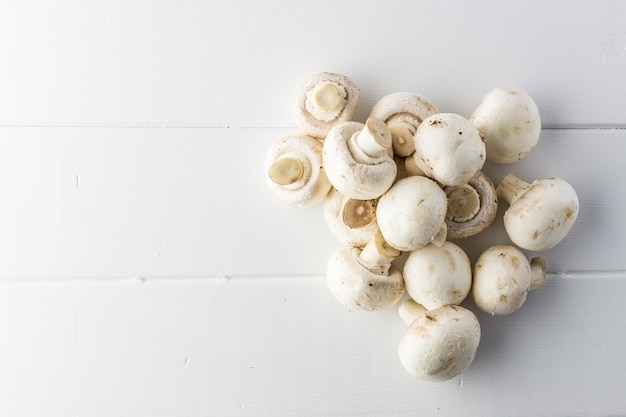 Fresh mushrooms champignon on a white wooden board