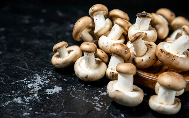 Fresh mushrooms champignons on the table On a black background