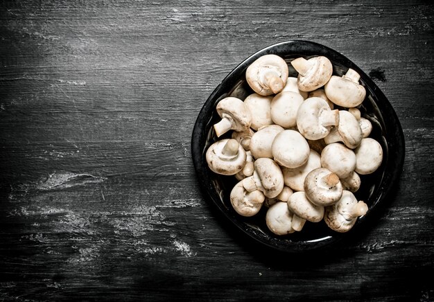 Fresh mushrooms on the plate. On a black rustic background.