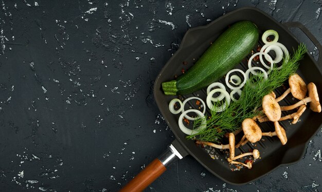 Fresh mushrooms with spices and herbs on black board. View from above. Copy space.