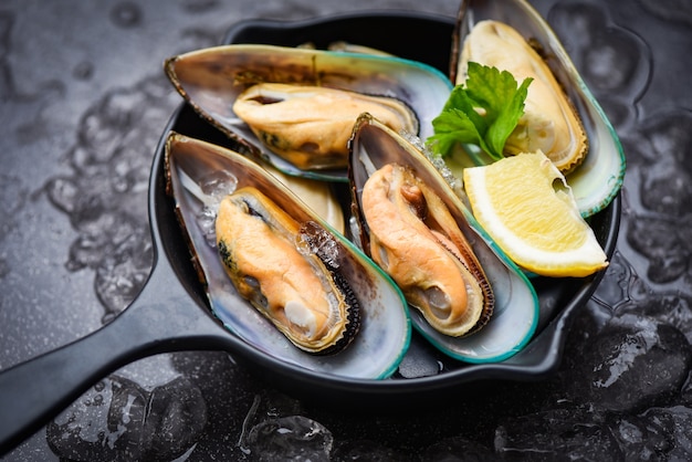 Fresh mussels on black bowl and ice