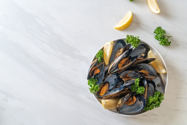 fresh mussels with herbs in a bowl with lemon