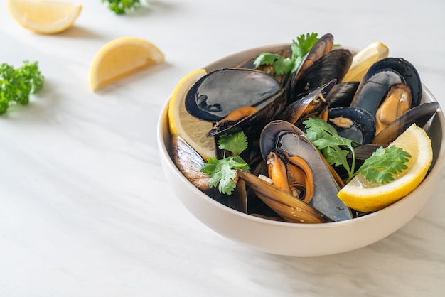 Cozze fresche alle erbe in una ciotola con il limone