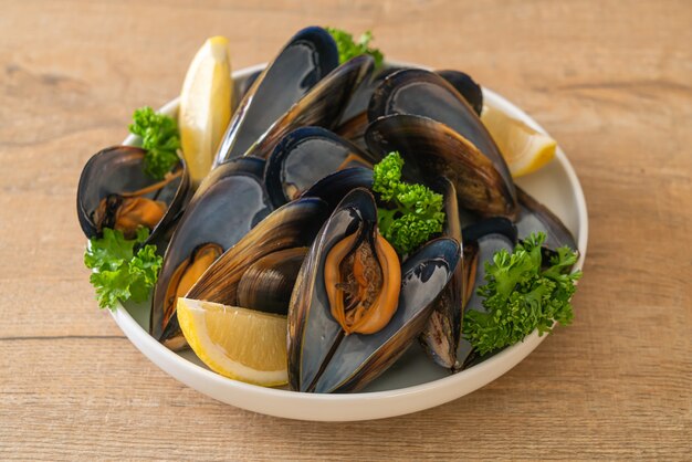 fresh mussels with herbs in a bowl with lemon