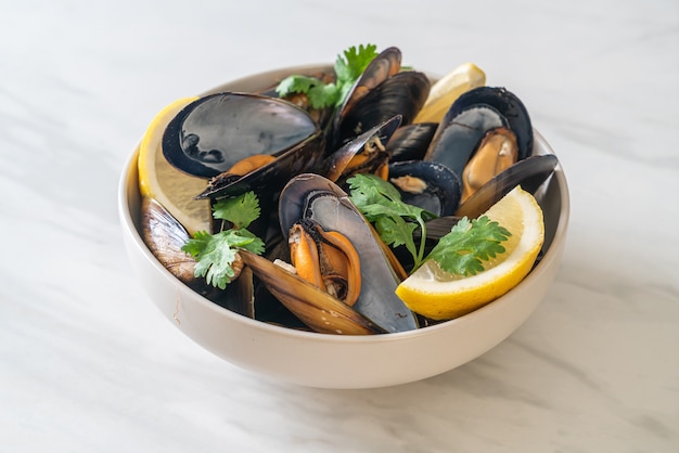 fresh mussels with herbs in a bowl with lemon