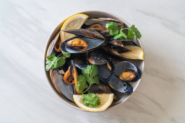 fresh mussels with herbs in a bowl with lemon