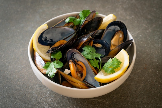 fresh mussels with herbs in a bowl with lemon