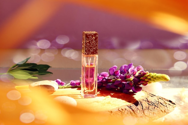 Fresh natural fragrances eau de toilette bottle with blooming lupine branch in water splash bokeh closeup