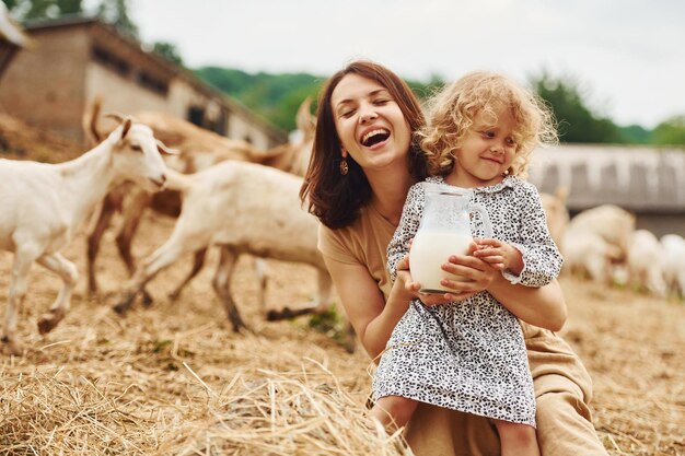 Fresh natural milk Young mother with her daughter is on the farm at summertime with goats