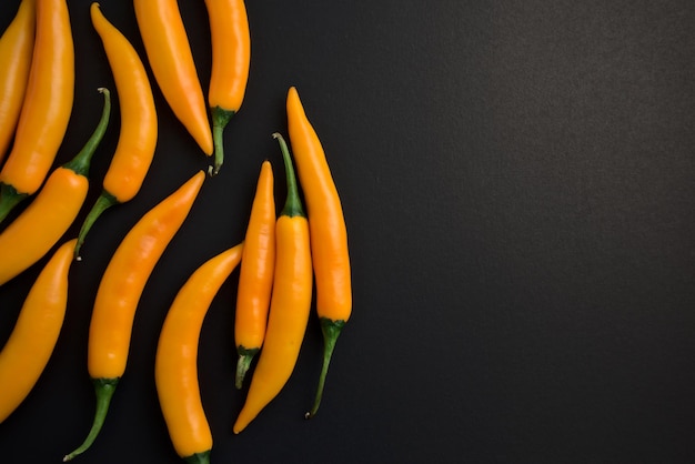 Fresh natural vivid yellow chillis flat lay on black grunge background