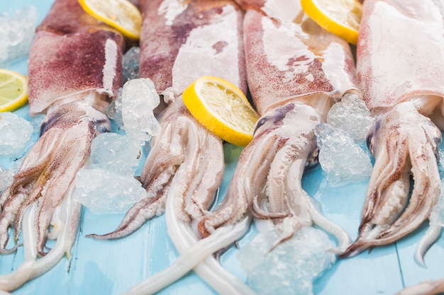 Fresh octopus or squids raw on wooden board with ingredients