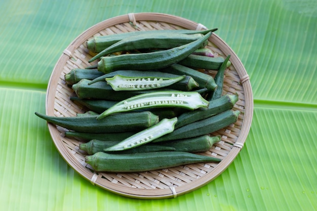 Fresh okra in round bamboo basket on banana leaf