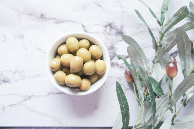 Olive fresche in un contenitore e foglia sul tavolo