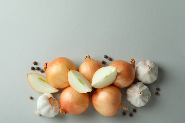 Fresh onion and peppercorns on light gray background